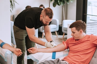 nurse administers iv hydration therapy to man at home